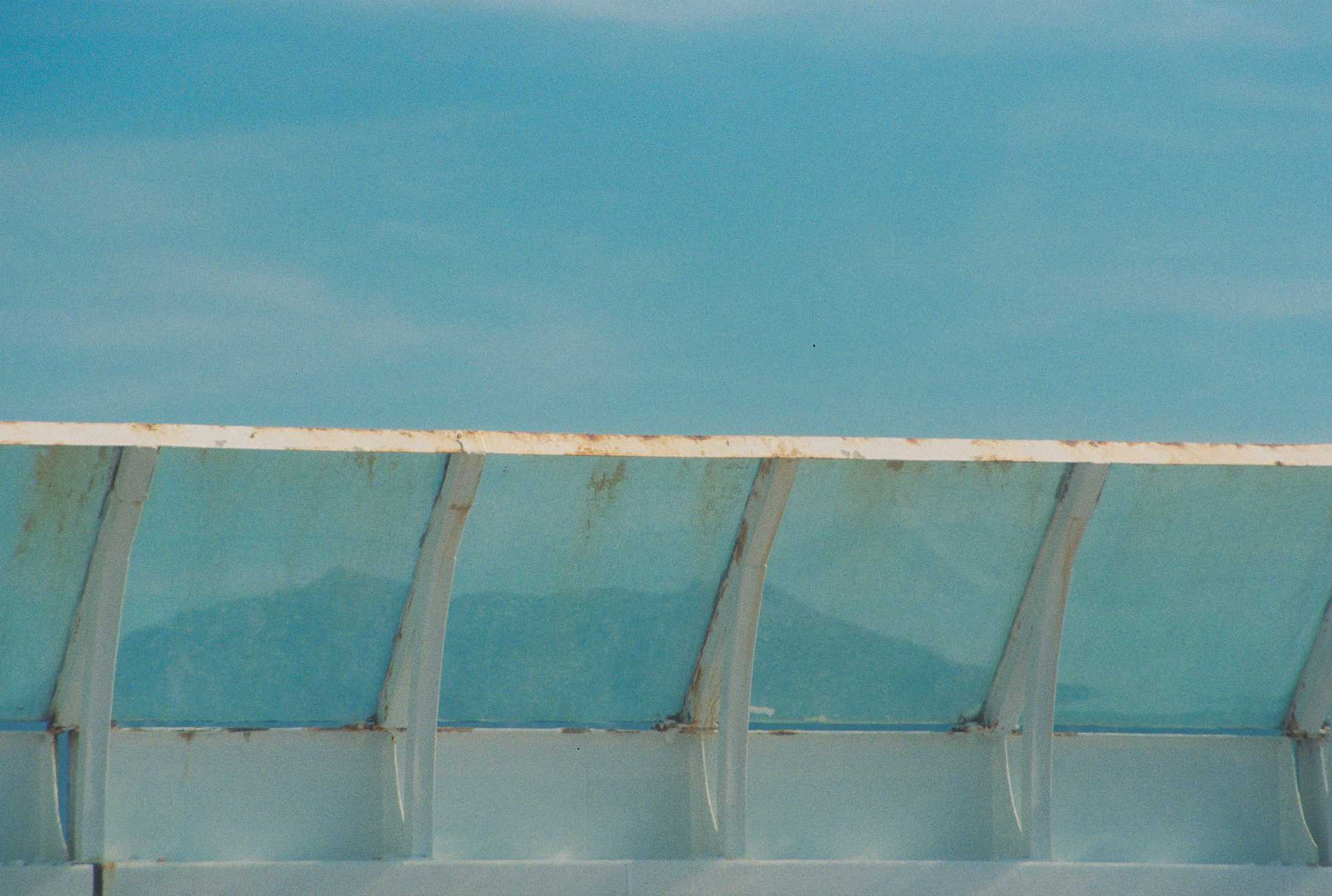 Mountains through dirty glass panels on a ferry