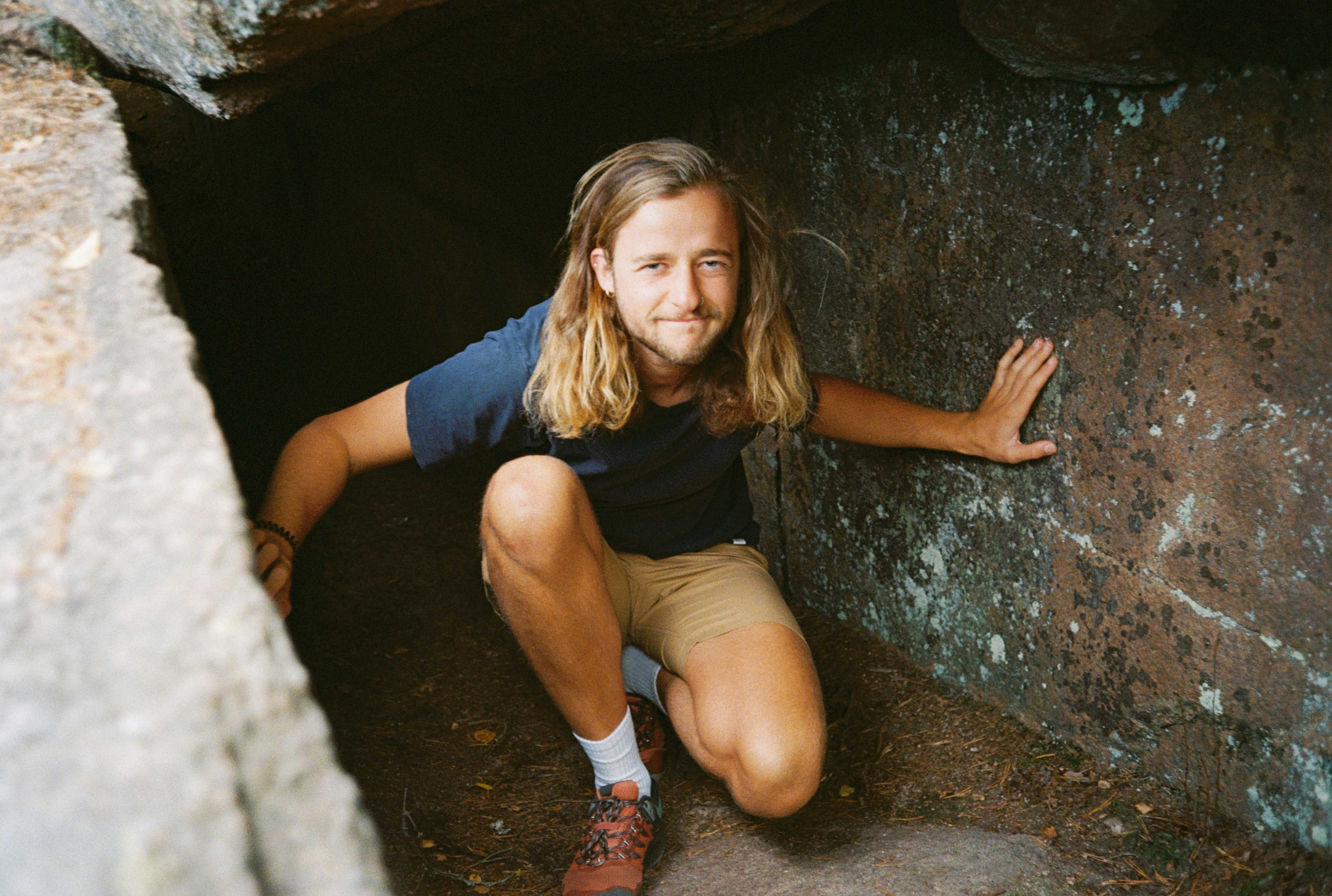 Image of Anton Brall sitting in a small cavern