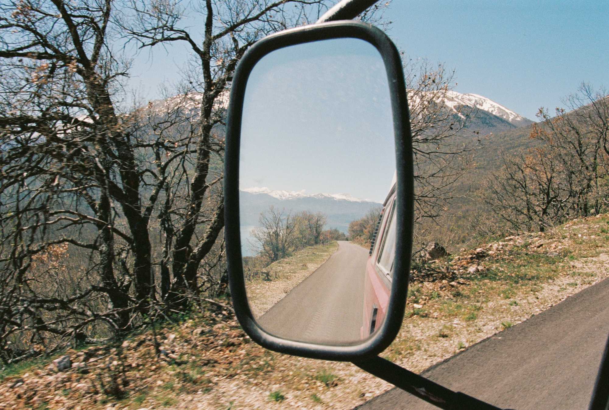 driving up a hill with the mountains in the rear view mirror